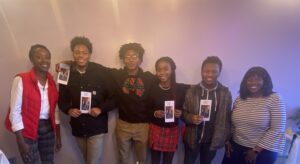 Liberated Success students and teacher pose together smiling and holding program brochures