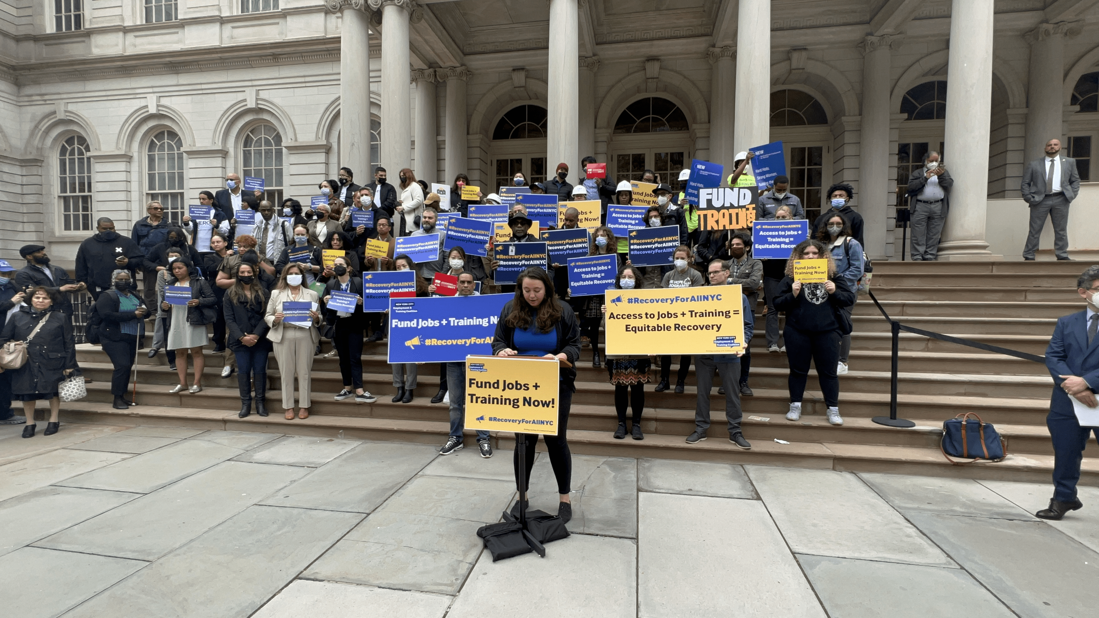 Coalition members on the steps of City Hall holding signs that read "Fund Jobs and Training Now"
