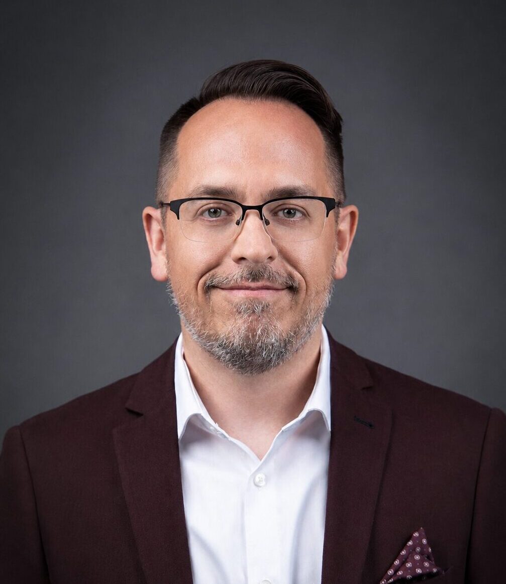 Gregory J. Morris headshot wearing a white shirt and burgundy blazer.