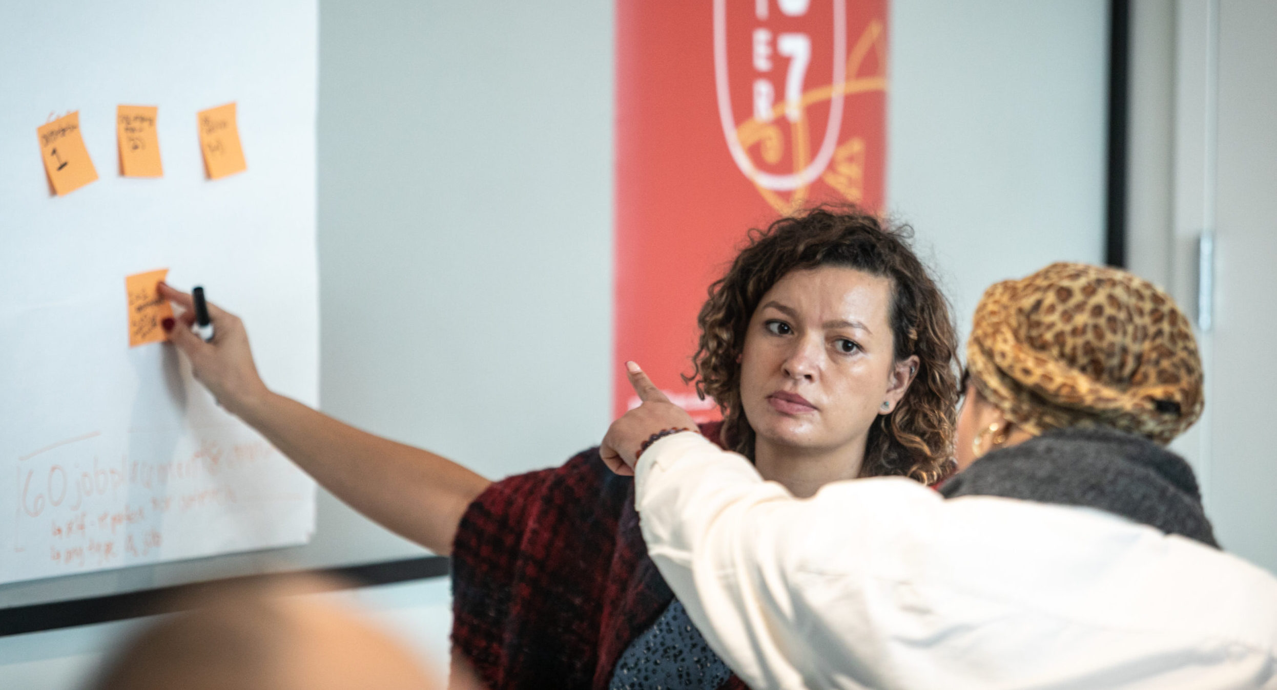 A woman pointing at a set of post-it notes on a whiteboard