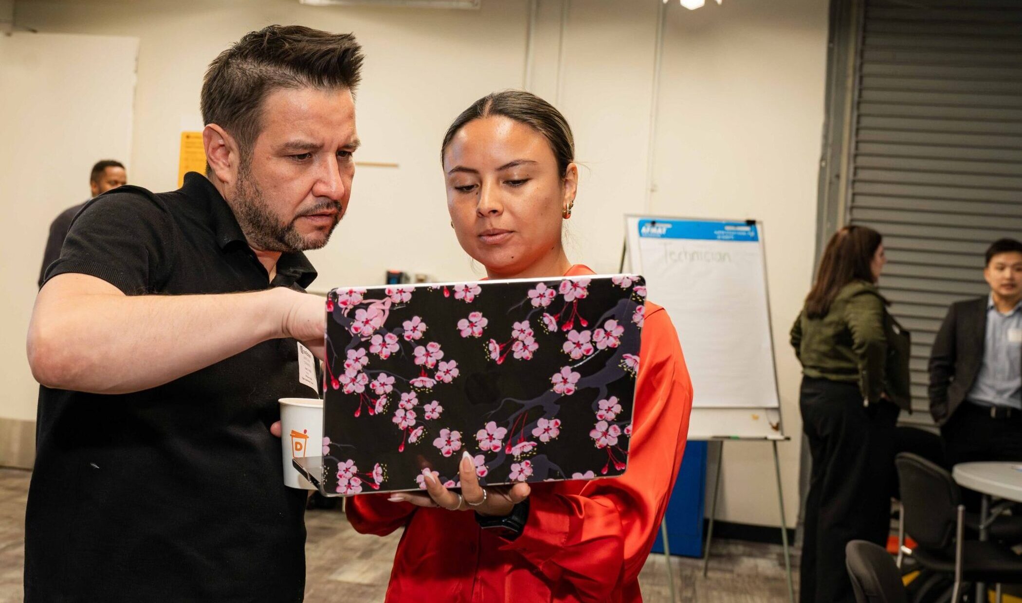 A man and woman stand together looking at a laptop.