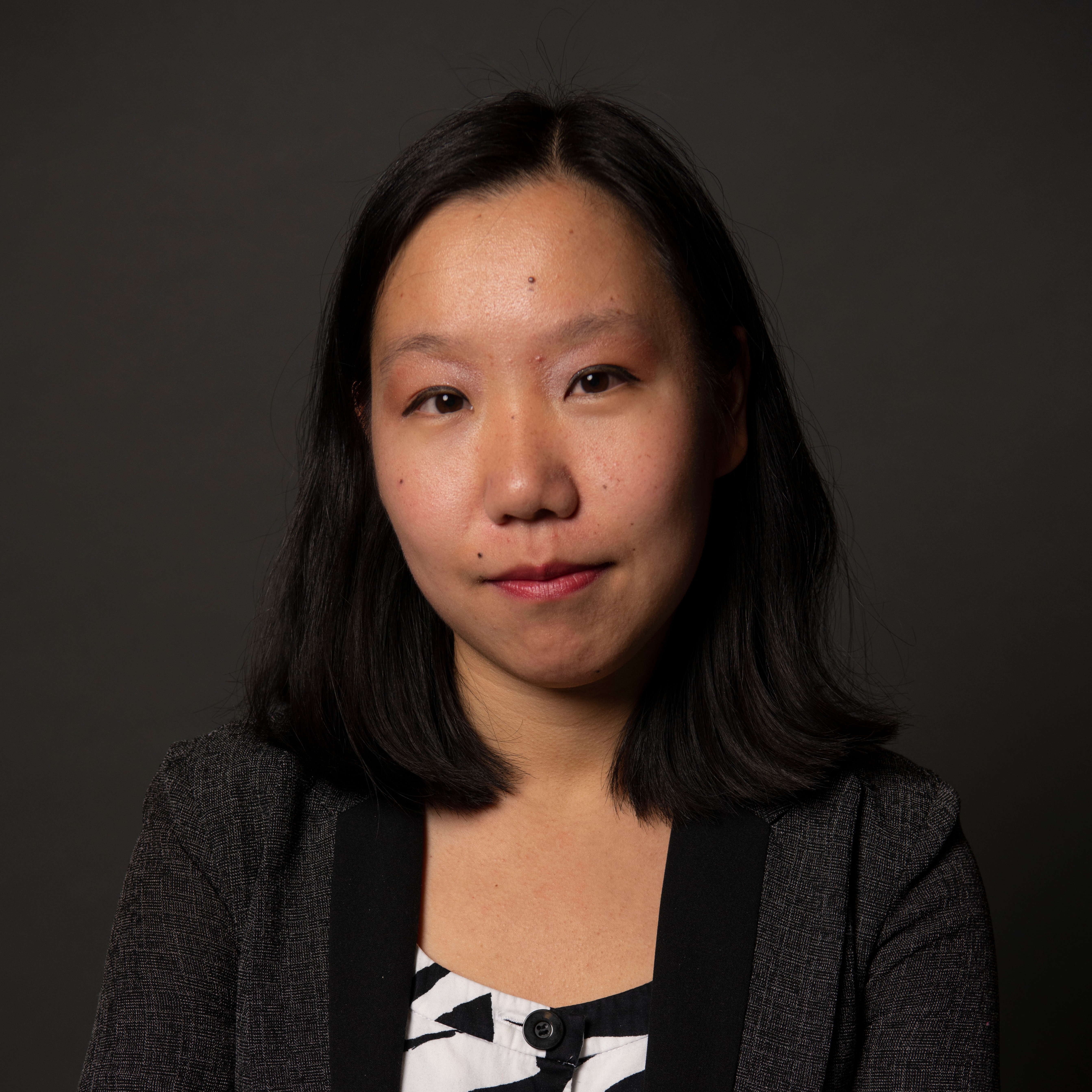 Marina Fang's headshot wearing a dark blazer and black and white shirt.
