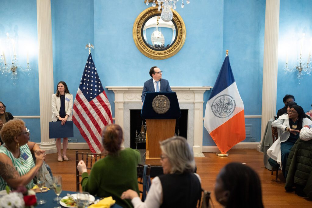 A photo of Gregory J. Morris at the podium with early childhood educators in the audience at Gracie Mansion.