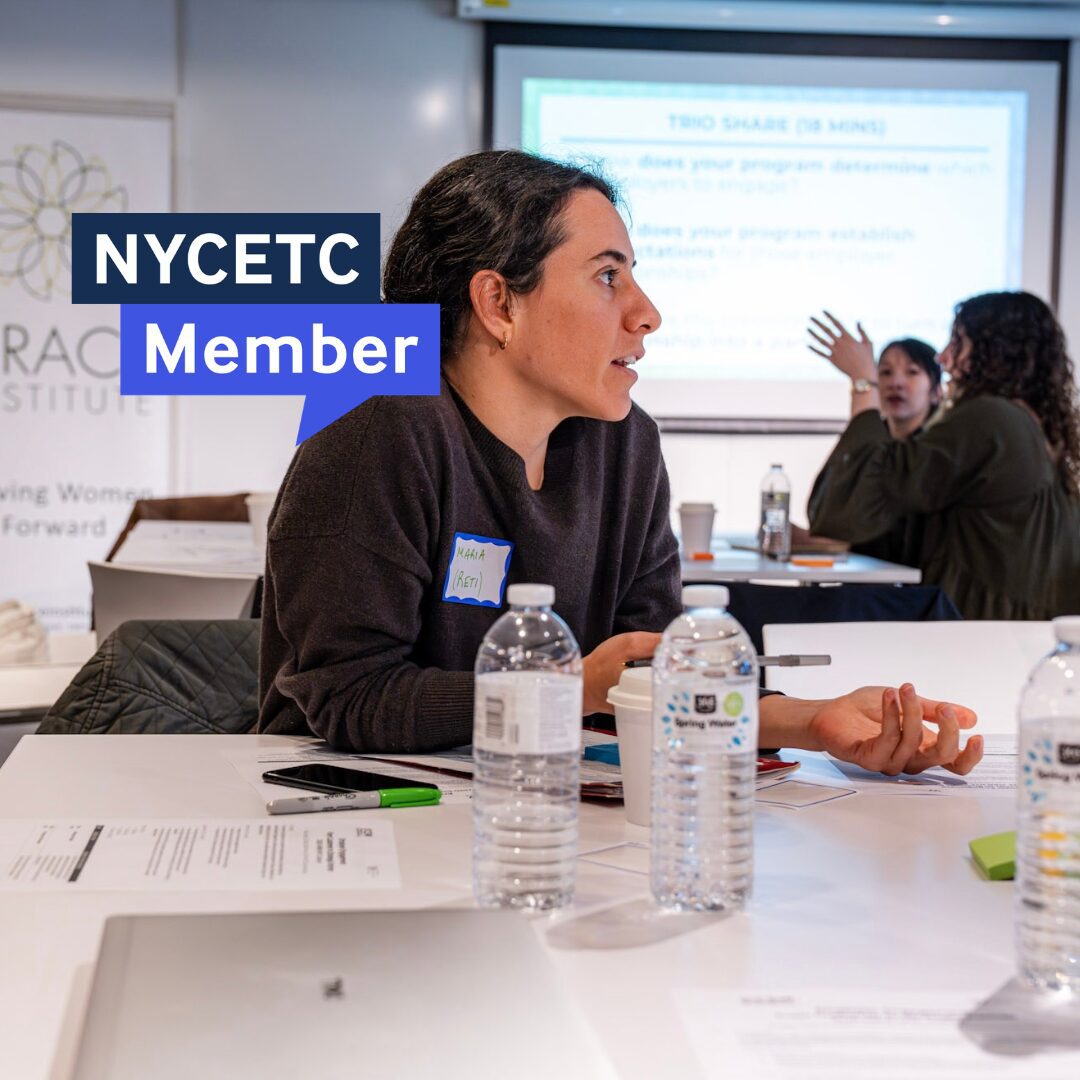 A young professional wearing a black top participates in a meeting with papers on a table.